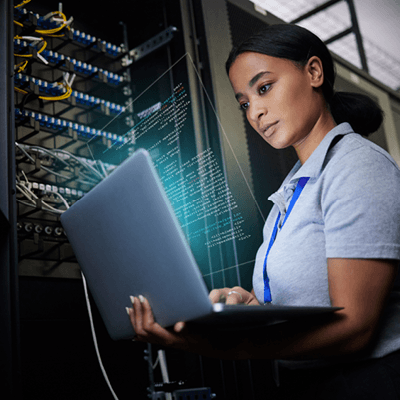 IT professional working in a computer server room holding a laptop